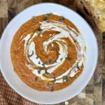 Creamy red lentil tomato soup in a bowl topped with herbs — cozy, high-protein, and perfect for an easy weeknight dinner.