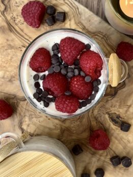 Jar of raspberry chocolate overnight oats topped with fresh raspberries and mini chocolate chips, high-protein healthy breakfast for muscle building.