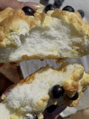 Lemon cloud bread broken open showing a soft, fluffy interior with blueberries on top, light and airy texture made from whipped egg whites