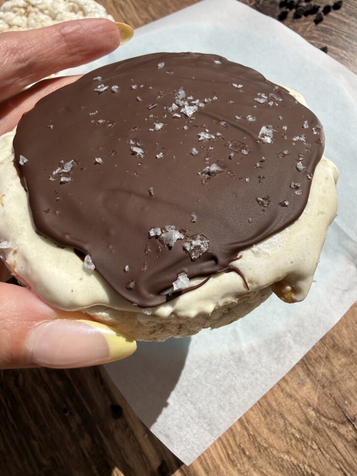 High-protein frozen rice cake s’mores topped with melted chocolate and flaky sea salt, made with coconut whipped topping and protein powder for a healthy dessert option.