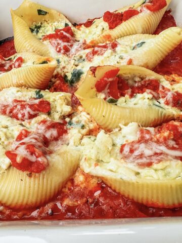 Powerhouse stuffed shells filled with a creamy high-protein mixture of cottage cheese, tofu, spinach, basil, and mozzarella baked in marinara sauce. Cozy vegetarian comfort food recipe from the More Protein cookbook, perfect for meal prep, family dinners, and high-protein weeknight meals.