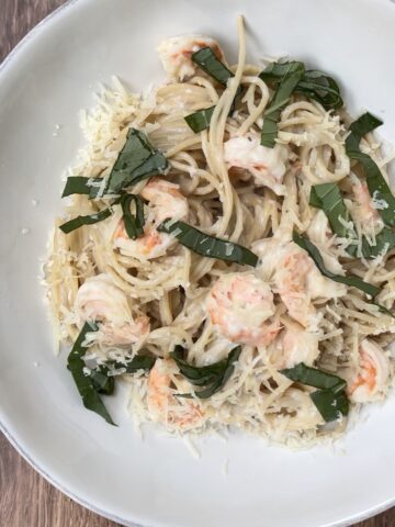 Creamy shrimp pasta made with spaghetti noodles, parmesan cheese, fresh basil, and sautéed shrimp served in a white bowl. Cozy Italian-inspired seafood pasta recipe perfect for weeknight dinners, date nights, and comforting homemade meals.