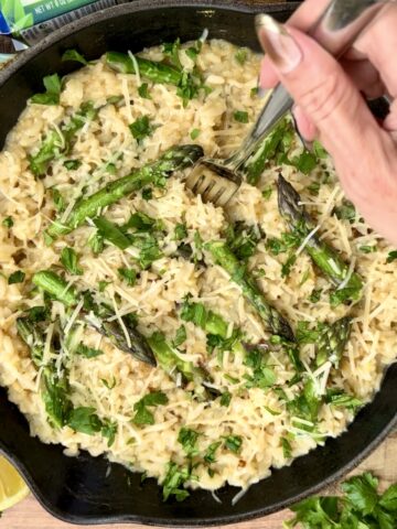 Creamy asparagus and lemon risotto made with arborio rice, fresh asparagus, parmesan cheese, herbs, and lemon in a black skillet. Cozy spring-inspired comfort food recipe with a rich creamy texture perfect for weeknight dinners and elegant homemade meals.